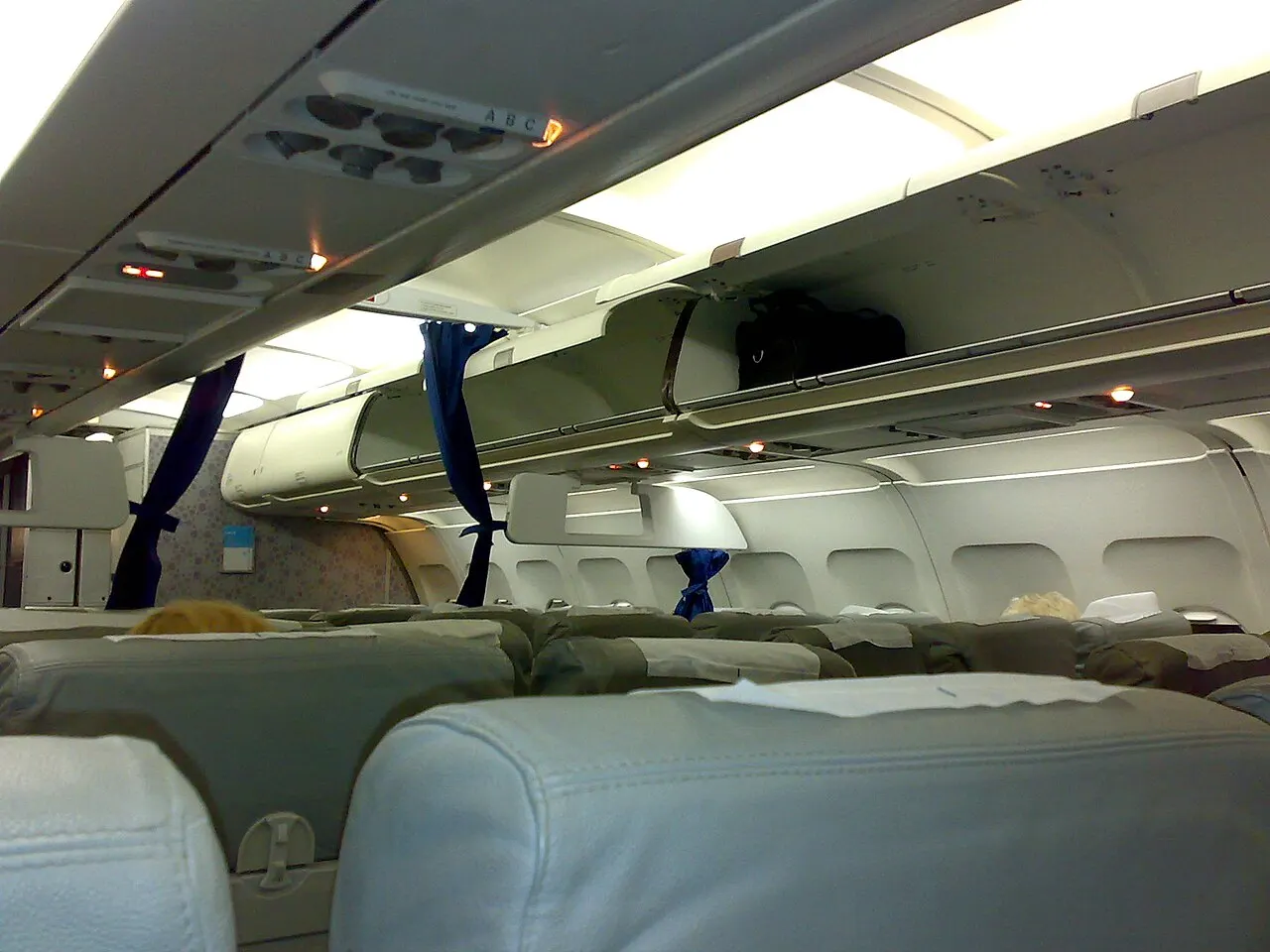 Cabine d'un Airbus A320 avec des rangées de sièges et les coffres à bagages ouverts avant l'embarquement
