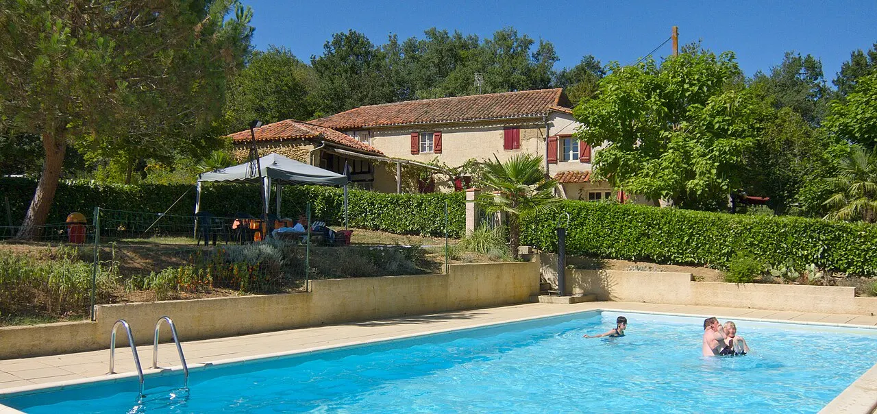 Piscine d'un camping à Pouylebon, dans le Gers, avec un bâtiment en arrière-plan